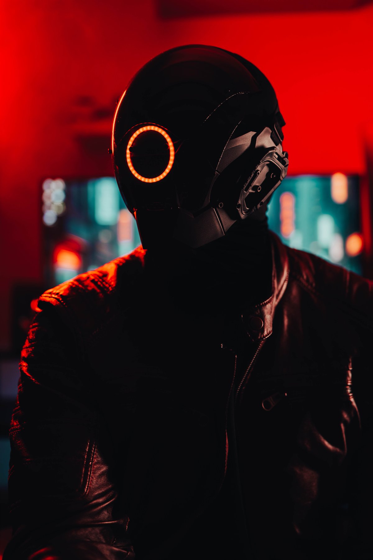 Retrato vertical de una figura con casco negro iluminada por luces rojas y azules.