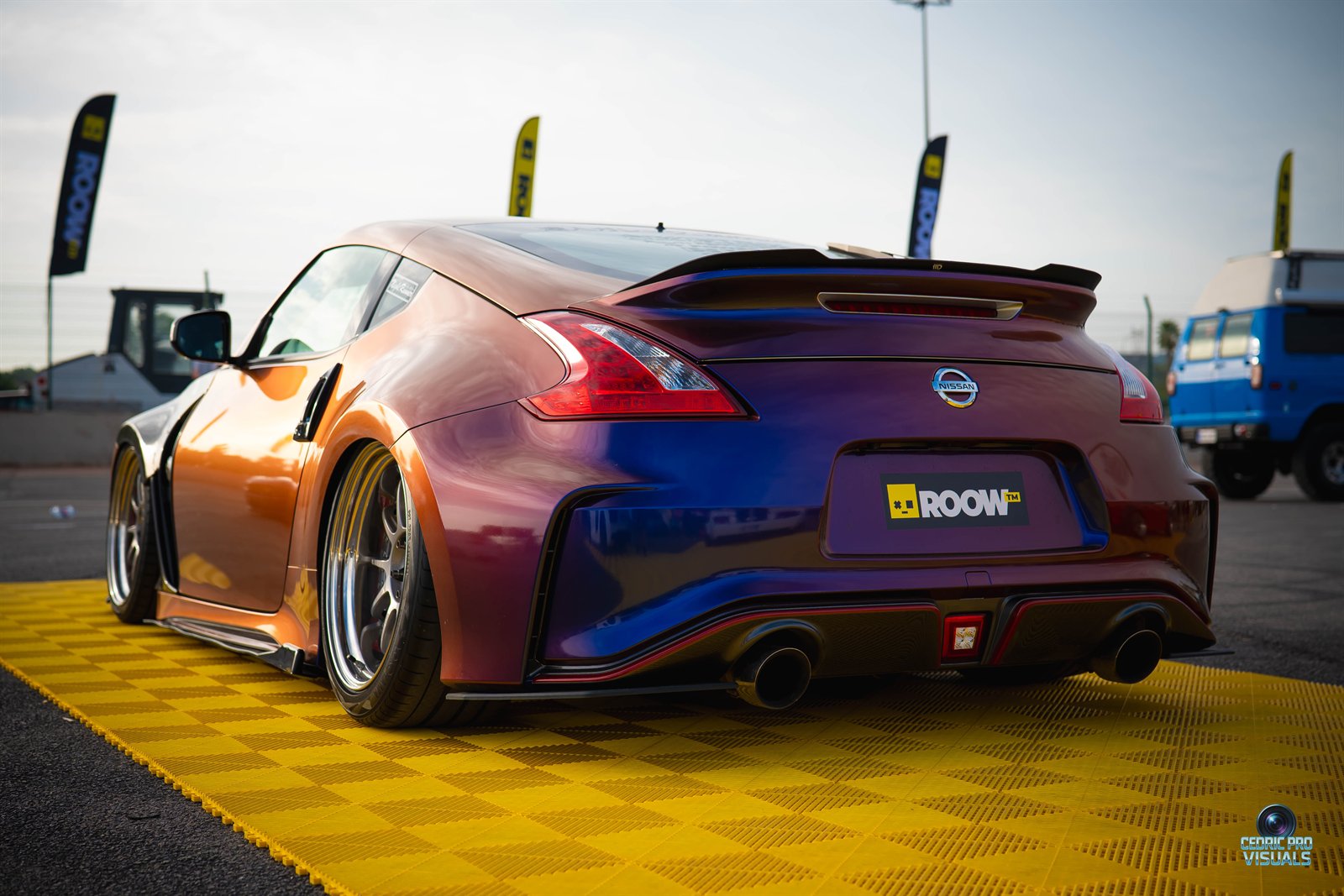 Coupé deportivo de color iridiscente expuesto sobre una plataforma amarilla.