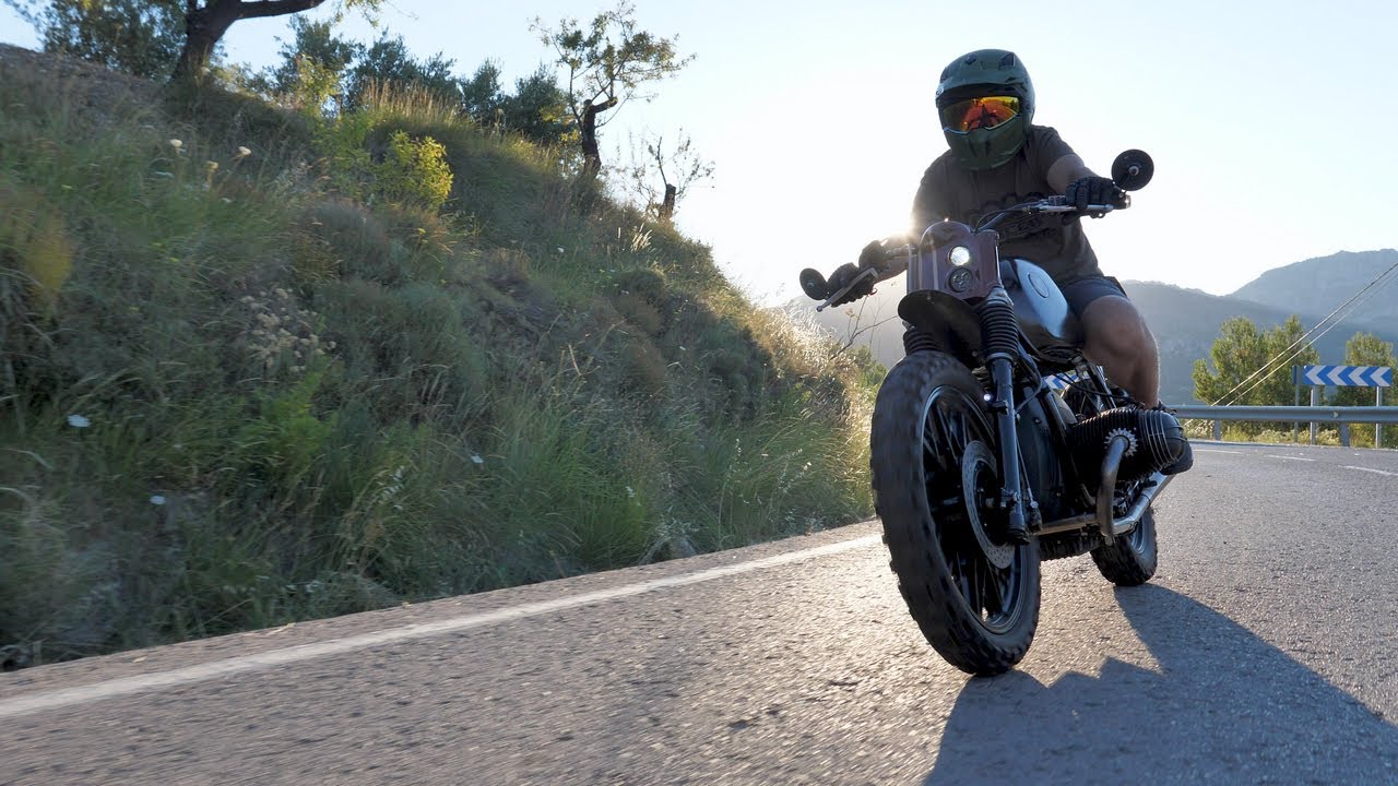 Motorista circulando con una motocicleta personalizada por una carretera de montaña.