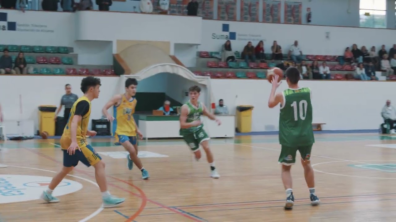 Jugadores disputando un partido de baloncesto en una cancha cubierta.