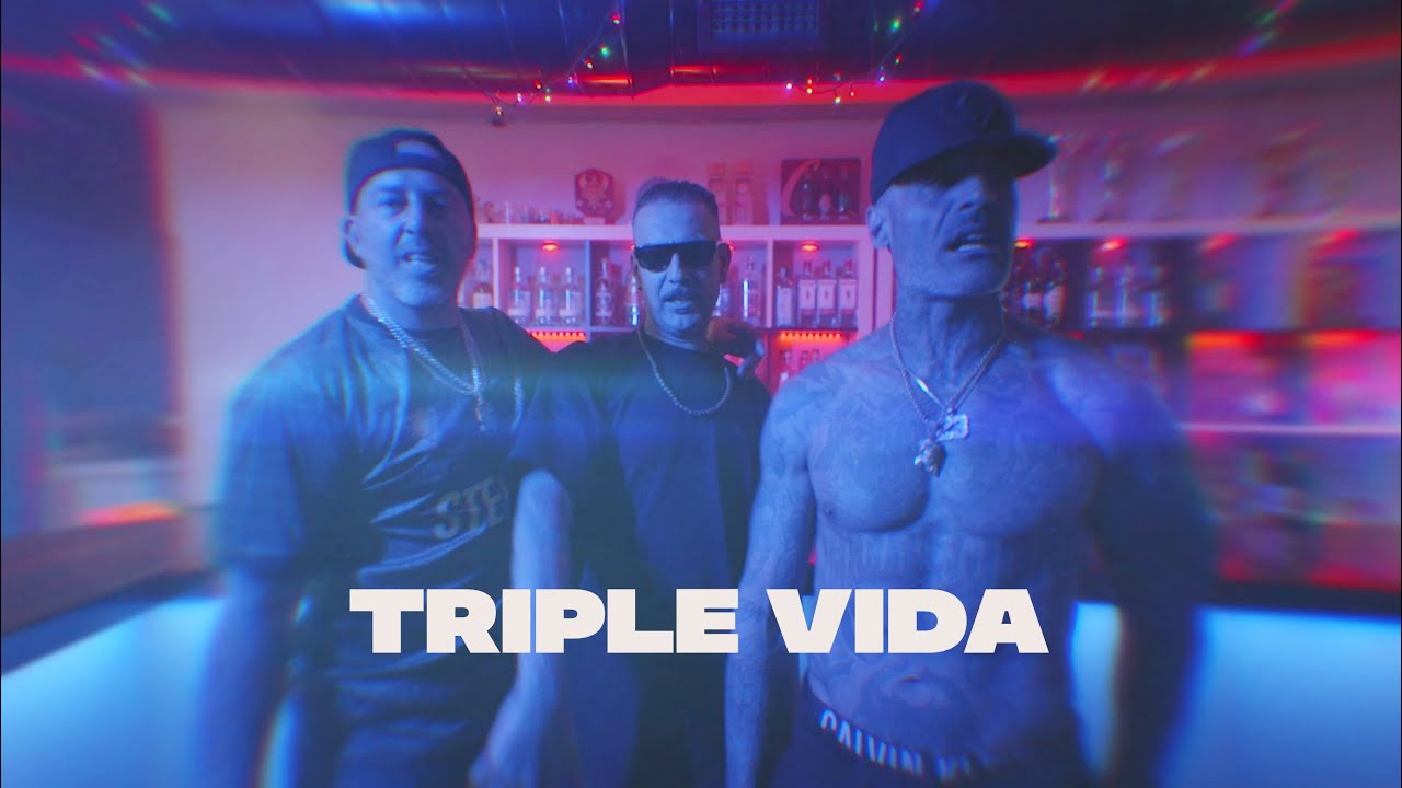 Tres hombres en un bar iluminado con luces azules y rojas.